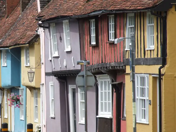 A row of timber-framed houses painted blue, cream, lilac, red and yellow on Castle Street in Saffron Walden.