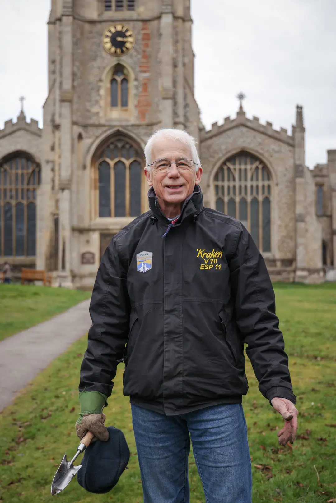 Edward Gildea holding a trowel in a churchyard, during a snowdrop planting