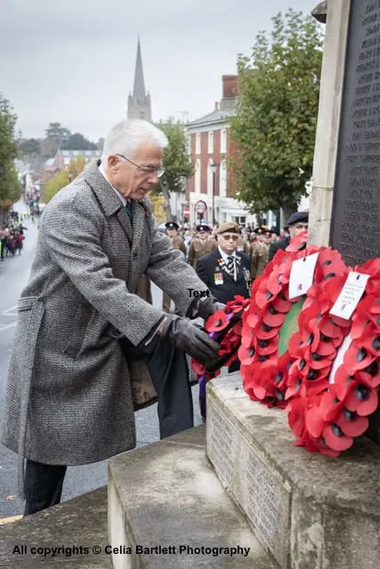 Edward Gildea, in an overcoat, laying a wreath of poppies at the Saffron Walden war memorial on 11 November 2023