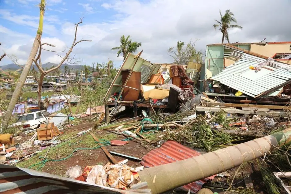 Homes reduced to wreckage of timber and corrugated iron among stripped palm trees after a cyclone in Fiji