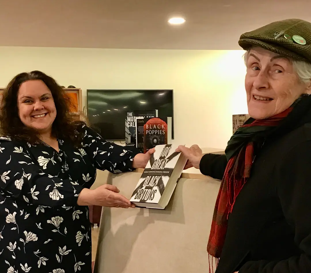 Two people handing over a book in a library.