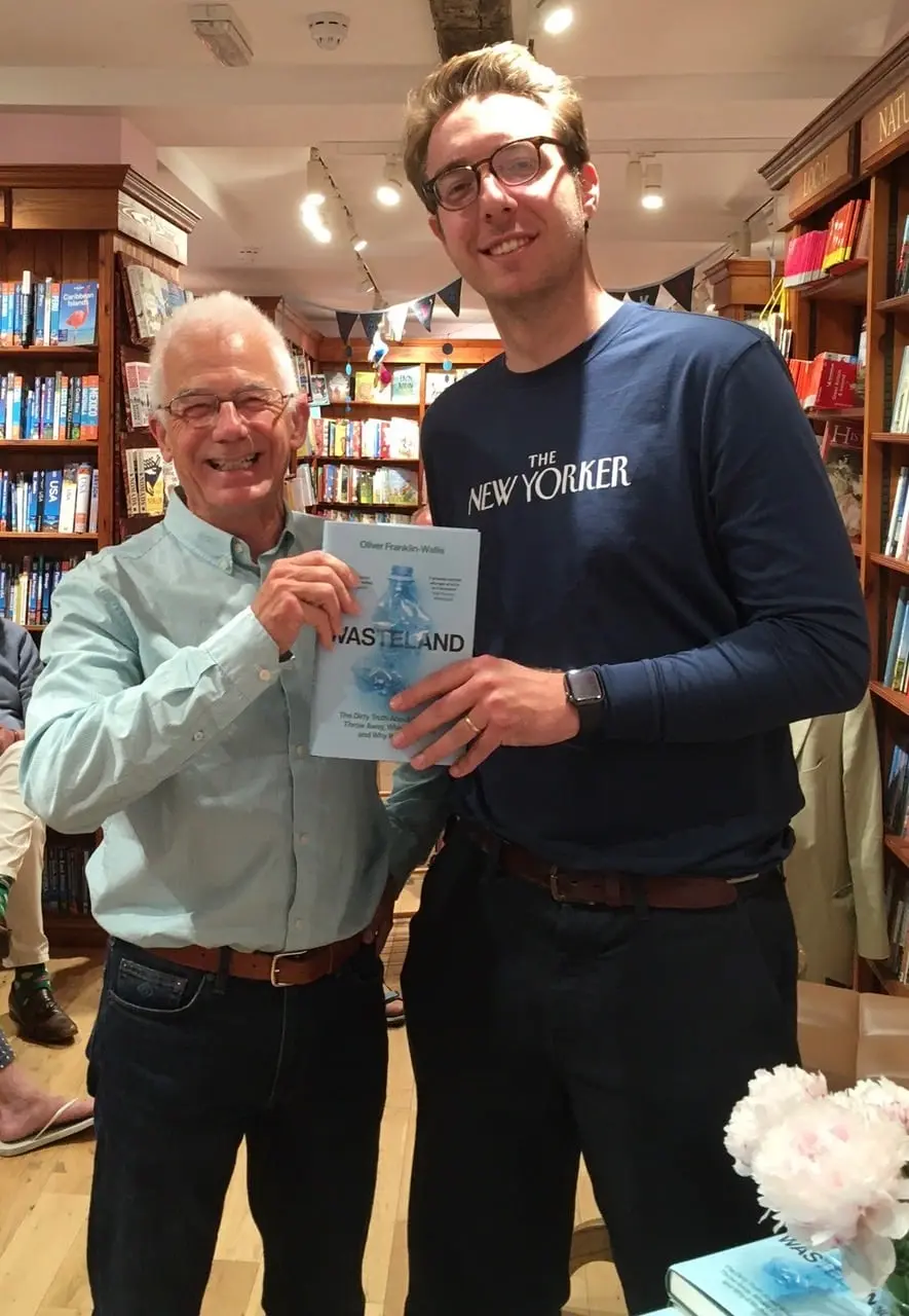 Two men in a bookshop, one holding a copy of the book Wasteland.